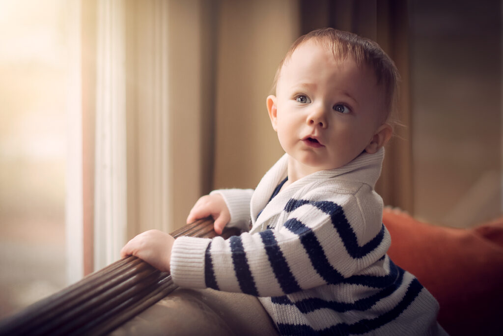 toddler posed near bright window during at home photography session